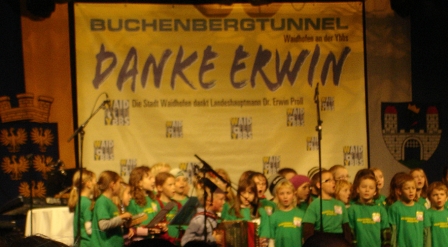 Kinderchor in grünen T-Shirts vor einem großen Plakat mit den Worten "Danke Erwin"